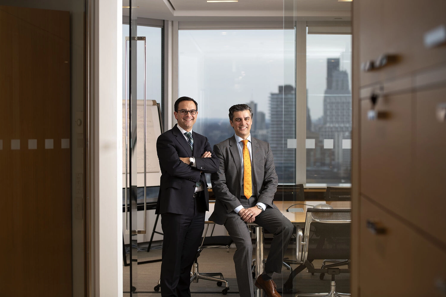 Two business executives pose in a board room of a downtown office