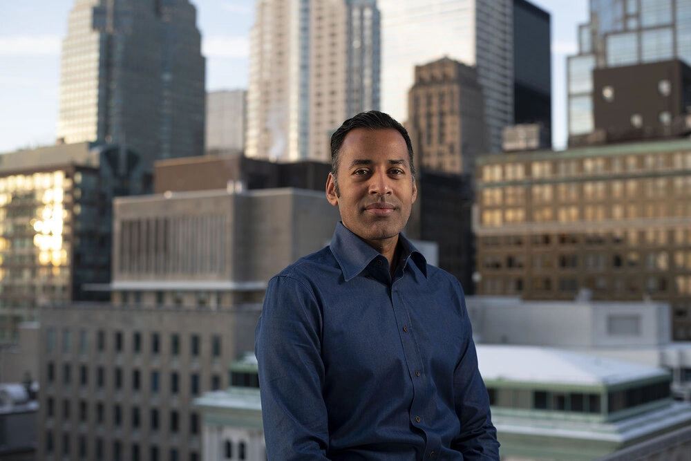 A business headshot photographed on a roof in downtown toronto. The city can be seen in the background.