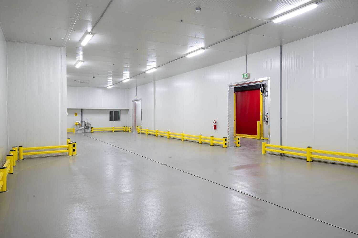 The image is of a cold storage warehouse interior. The warehouse is large and empty, with concrete floors and white walls.  