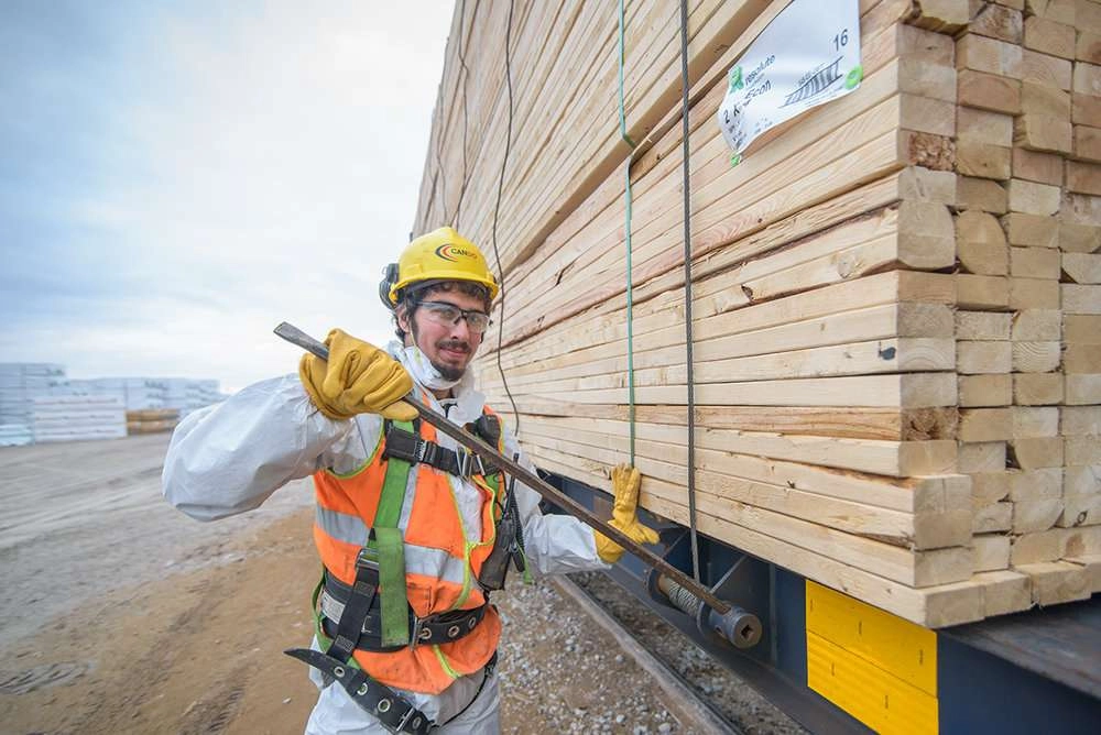 Worker tightens straps on lumber