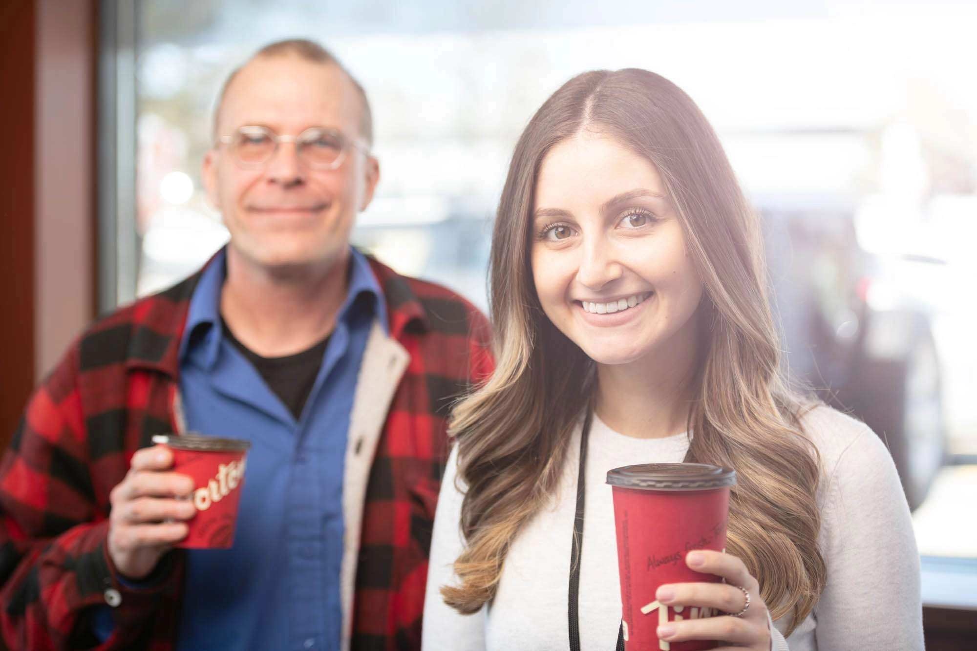 One counselor holds a coffee cup while a client stands in the background.  