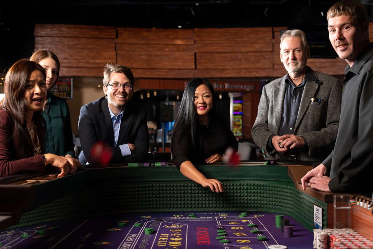 Player roles dice toward camera, in a casino table game. © robert lowdon