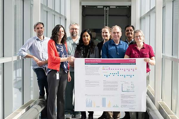 Medical research team members hold a progress chart
