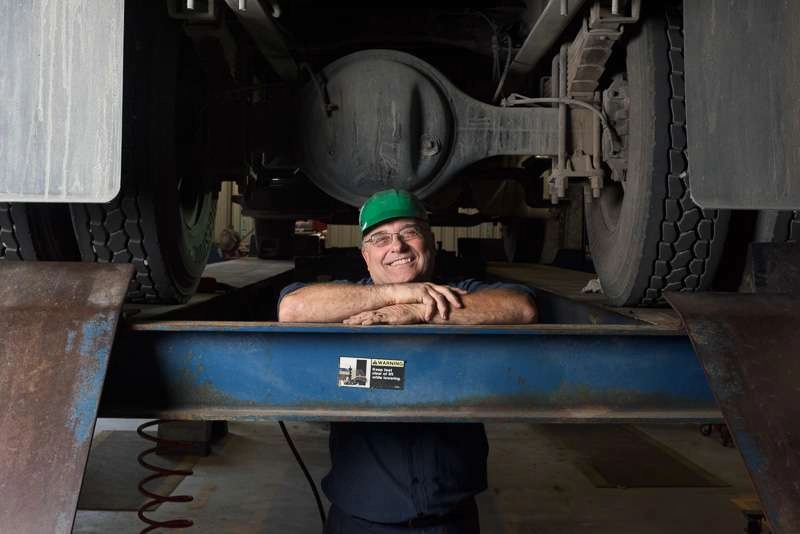 A mechanic poses between the tires. This image i am using a 45 degree angle of lighting and using natural light in the machine shop for fill.