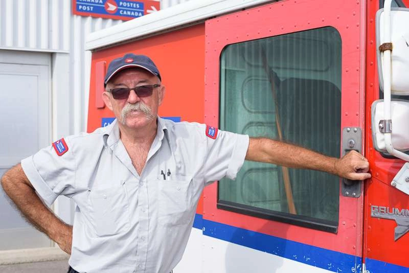 Mail carrier leans on mail truck at canada post facility in toronto