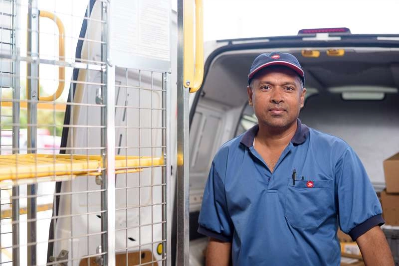 Post worker with mail cage outside vehicle
