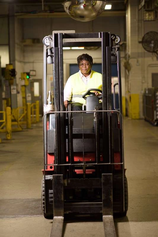 A employee drives a forklift across a dock. I used lighting placed to the left of the subject to highlight her in the environment.