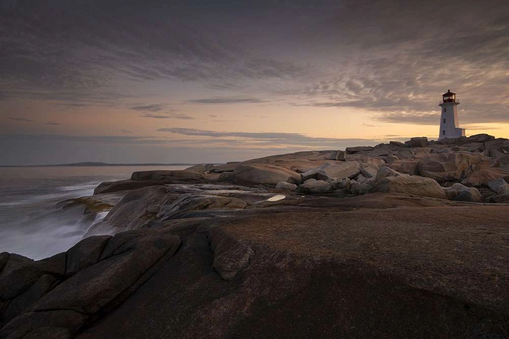 Early morning waves crash into the coast near the lighthouse. © robert lowdon