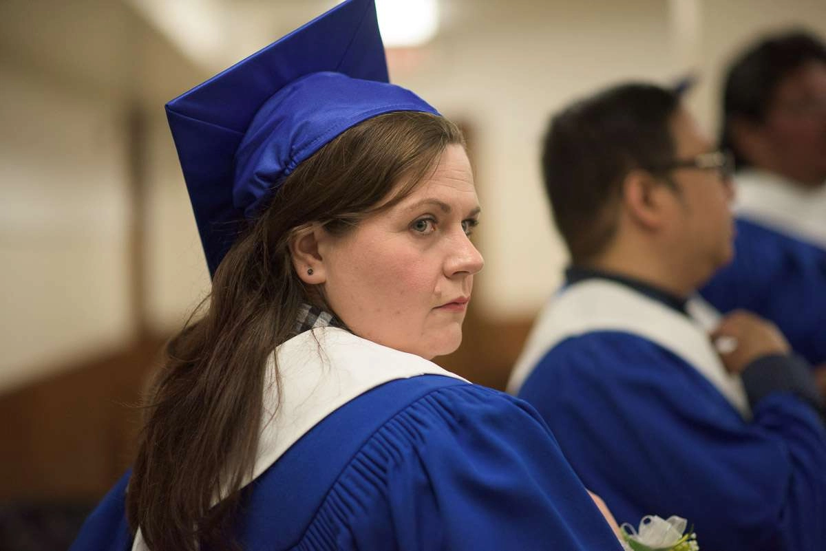 This close-up shot captures a graduate looking over their shoulder with a pensive expression on their face. A shallow depth of field is used to eliminate noise in the background and make the subject the focus of the image.