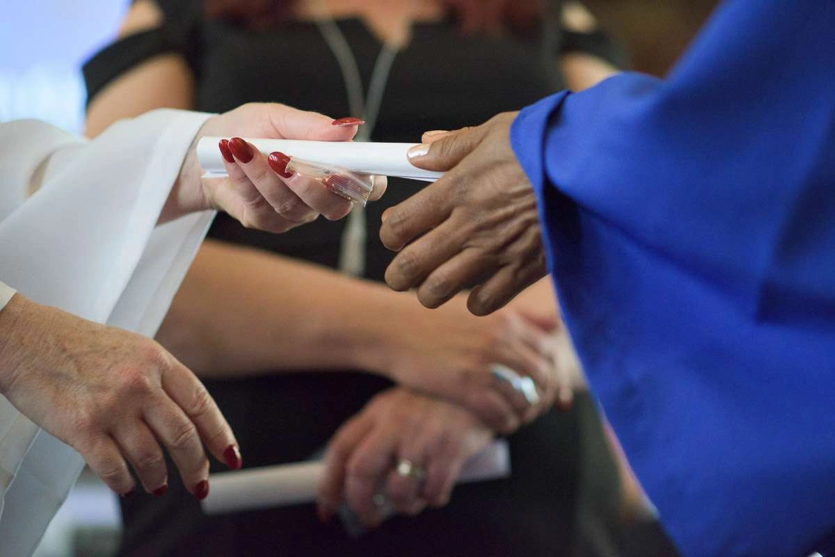 An instructor hands a diploma to a graduate. This close-up shot focuses on their outstretched hands, highlighting the significance of this moment.