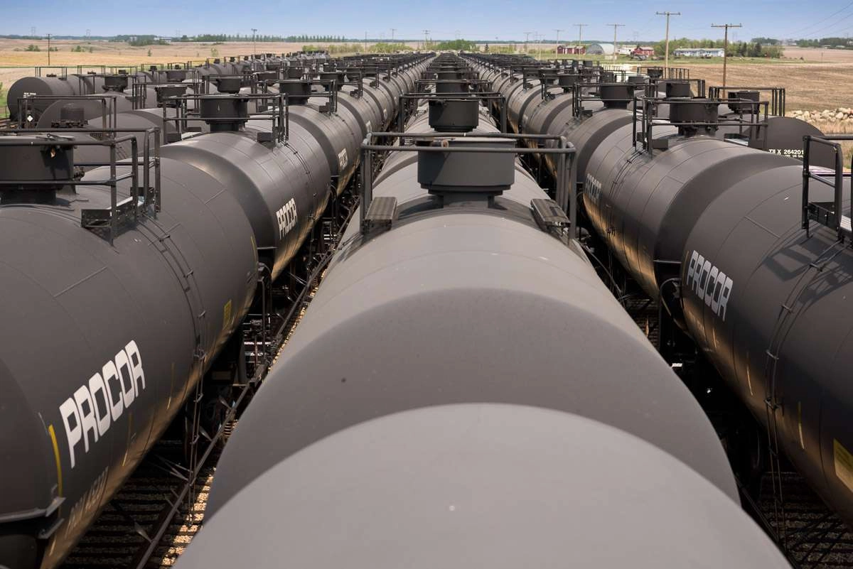 This image captures the view from on top of a tank car. The leading lines of the grey, cylinder-shaped, tank cars guide the eye towards the horizon. It is a powerful image, with the rows of train cars lining the tracks as far as the eye can see.