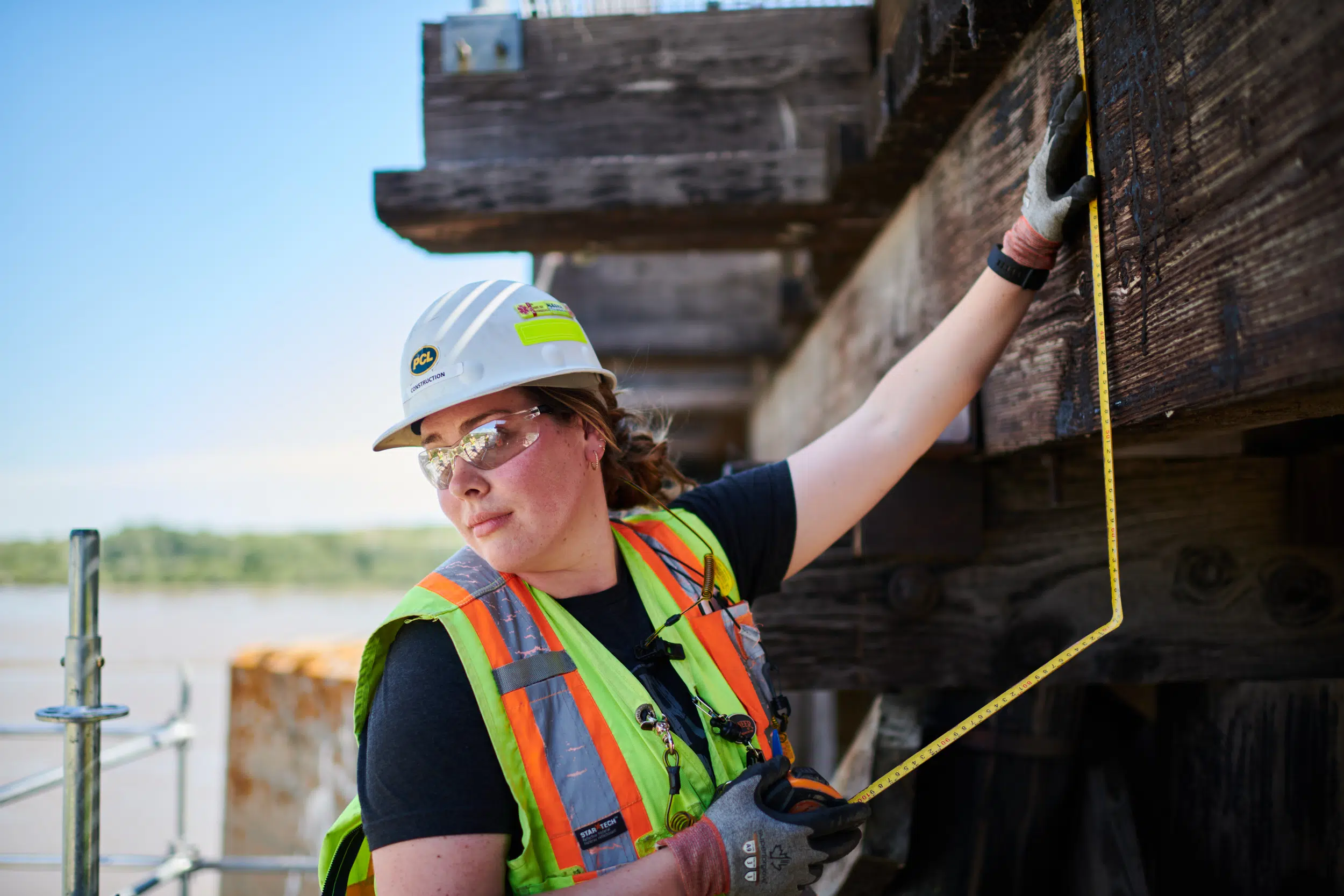 A construction worker measures old beams that are to be replaced on bridge.