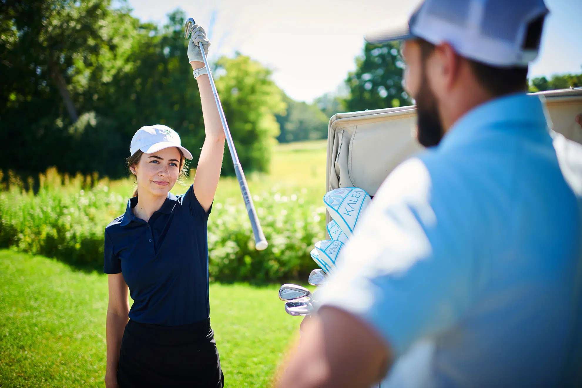 A female golfer removes a club from a golf bag.