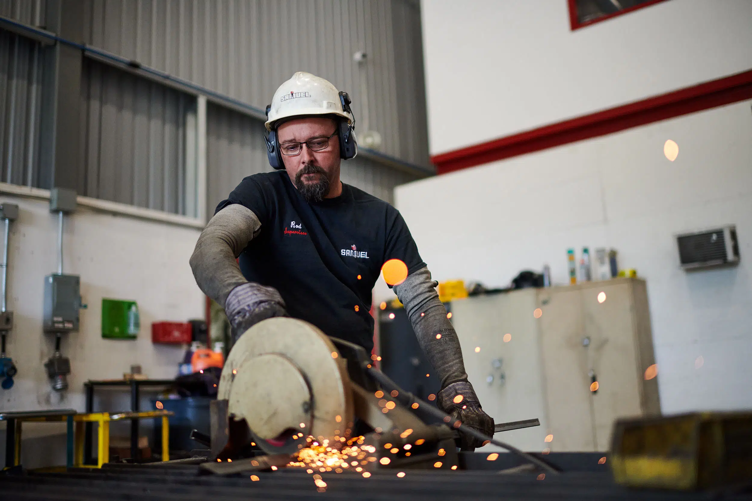 An employee cuts a piece of angle iron.