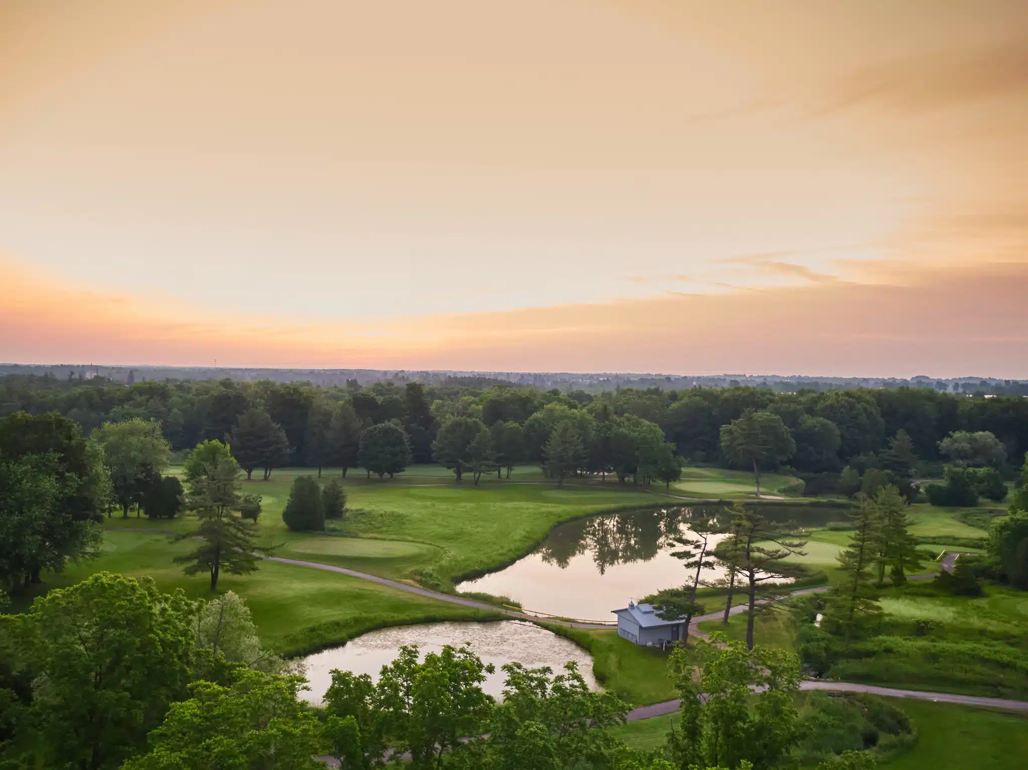 Aerial image of golf course during sunrise.