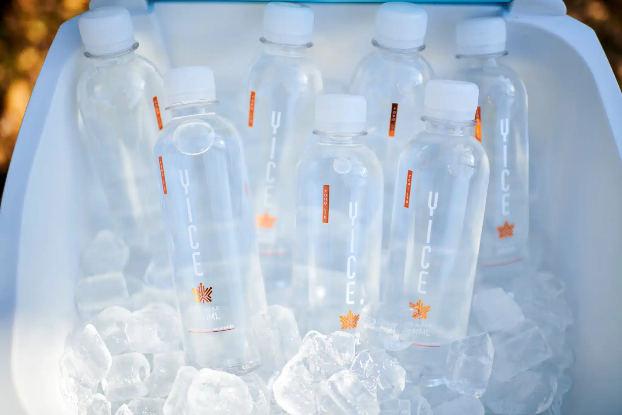 Multiple bottles of water staged in cooler on ice.