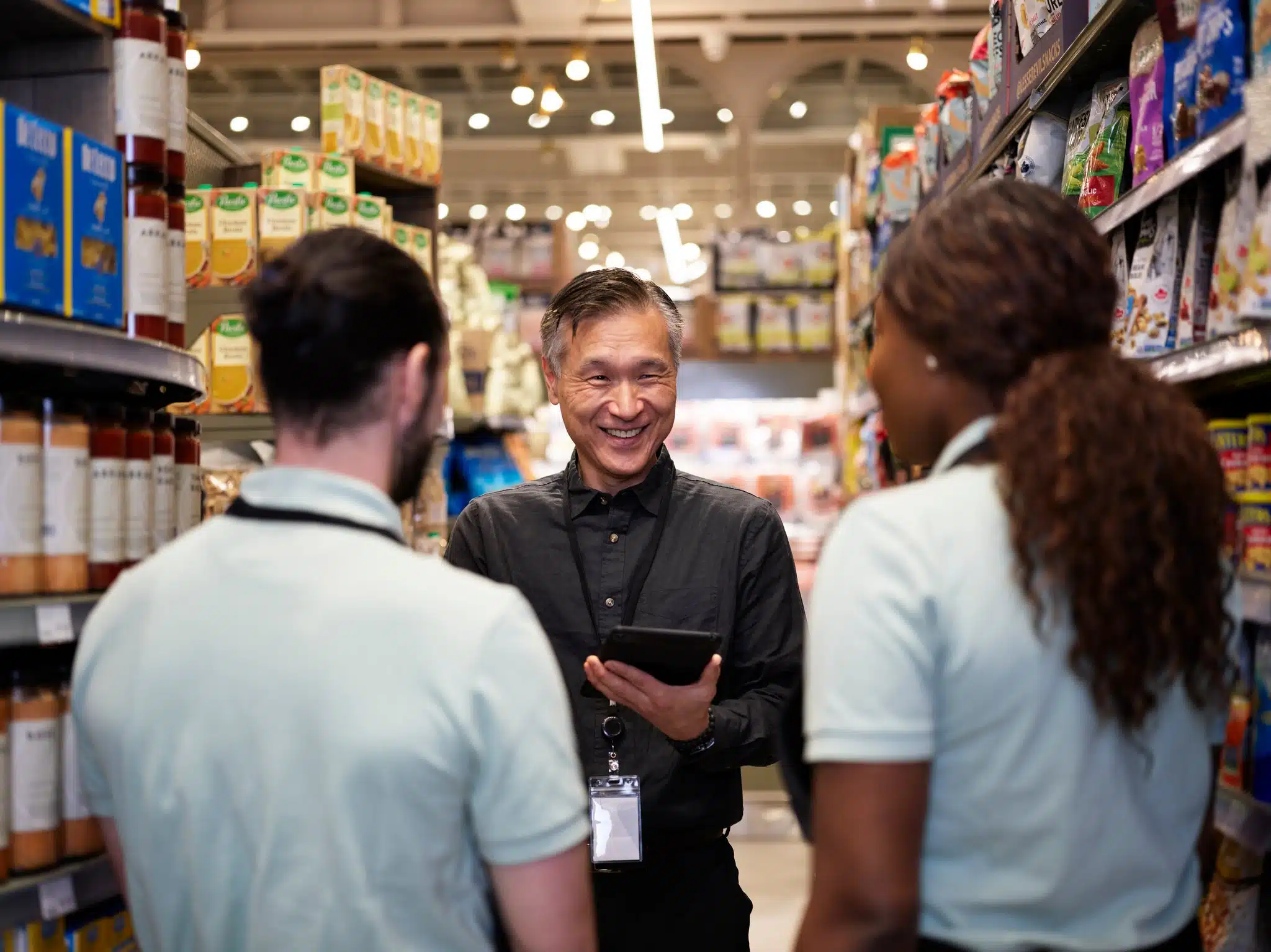 Grocery store manager training employees with technology.
